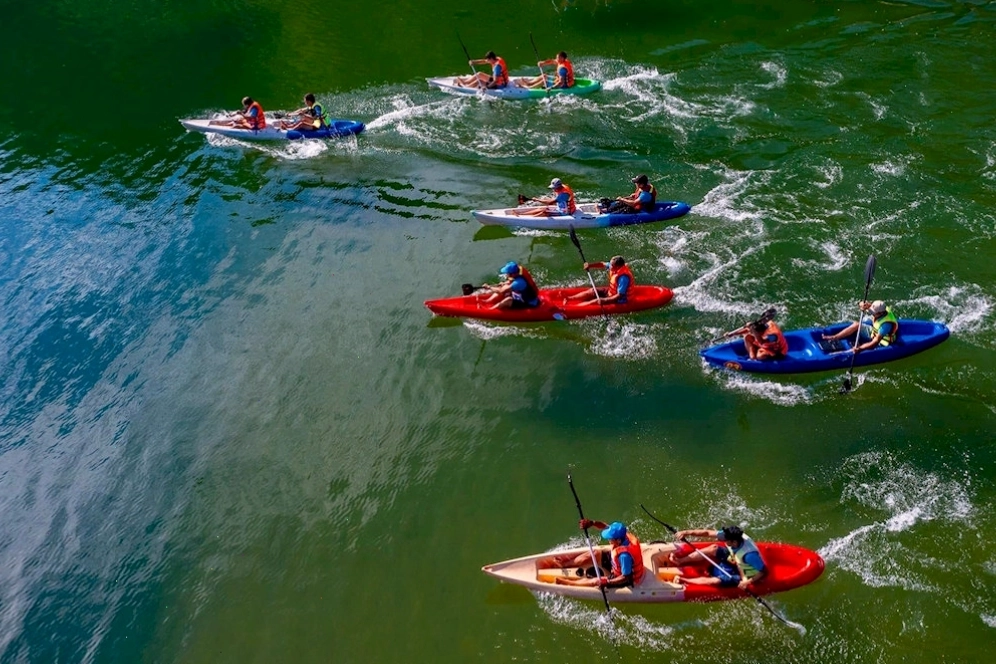 Du khách chèo thuyền kayak trên mặt hồ phẳng lặng